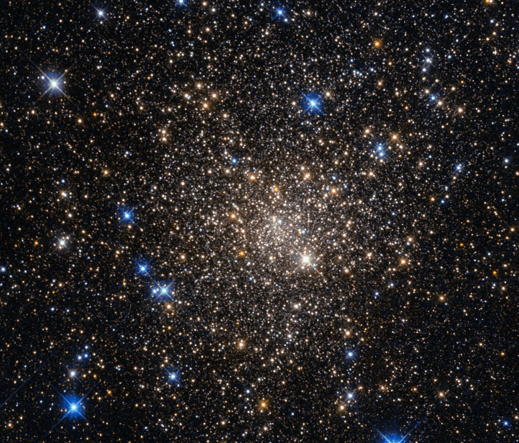 This image, taken with the Wide Field Planetary Camera 2 on board the NASA/ESA Hubble Space Telescope, shows the globular cluster Terzan 1. Lying around 20 000 light-years from us in the constellation of Scorpius (The Scorpion), it is one of about 150 globular clusters belonging to our galaxy, the Milky Way. Typical globular clusters are collections of around a hundred thousand stars, held together by their mutual gravitational attraction in a spherical shape a few hundred light-years across. It is thought that every galaxy has a population of globular clusters. Some, like the Milky Way, have a few hundred, while giant elliptical galaxies can have several thousand. They contain some of the oldest stars in a galaxy, hence the reddish colours of the stars in this image — the bright blue ones are foreground stars, not part of the cluster. The ages of the stars in the globular cluster tell us that they were formed during the early stages of galaxy formation! Studying them can also help us to understand how galaxies formed. Terzan 1, like many globular clusters, is a source of X-rays. It is likely that these X-rays come from binary star systems that contain a dense neutron star and a normal star. The neutron star drags material from the companion star, causing a burst of X-ray emission. The system then enters a quiescent phase in which the neutron star cools, giving off X-ray emission with different characteristics, before enough material from the companion builds up to trigger another outburst.